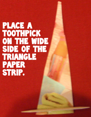 Place a toothpick on the wide side of the triangle paper strip.