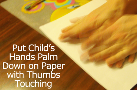 Put your child's hands, palms down, on paper with thumbs touching.