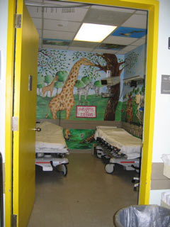 Look at this gorgeous, hand-painted wall that was beautifully painted by our volunteer artists where there is a monkey, trees, and a turtle can partially be seen on the right wall of Mt. Sinai's Pediatric ER Treatment Room